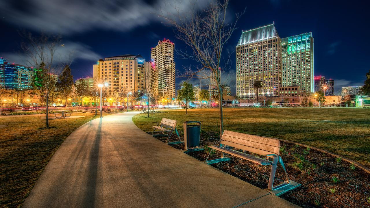 A downtown park at night with illuminated towers behind it